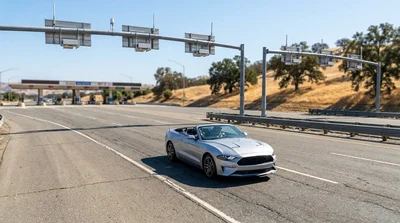 White car rental approaching a FasTrak toll plaza on a sunny California highway