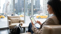 Driver holding a smartphone showing a map inside a car rental on a New York street