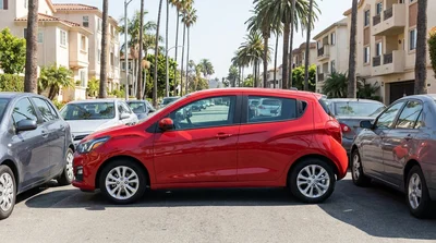 Small white car rental driving past palm trees on a sunny Los Angeles street