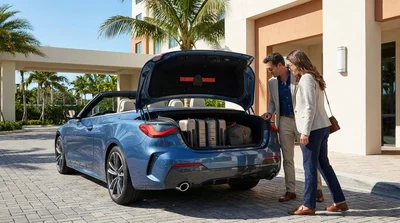 Suitcases in the open trunk of a car rental parked on a sunny street with palm trees in Miami