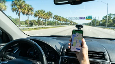 Smartphone displaying a navigation app on the dashboard of a car hire in Florida
