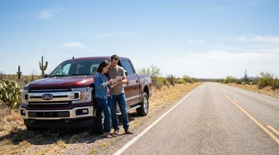 Driver standing next to a broken down car rental on the shoulder of a Texas highway