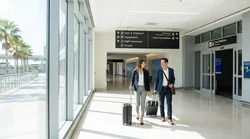 Travelers with luggage walking through the Orlando Airport terminal toward the car rental desks