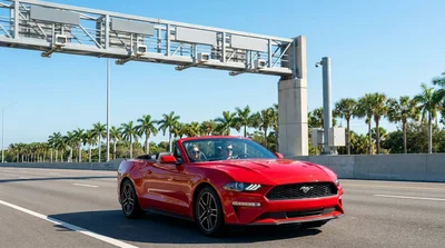 Driver approaching a highway toll plaza in an Orlando car rental on a sunny day