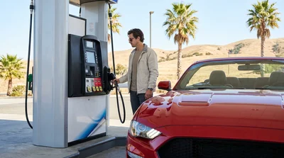 Close-up of fuel grade labels on a gas pump beside a car rental at a California gas station