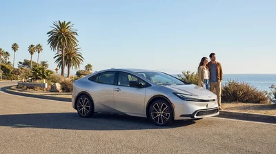 White hybrid car rental driving along a scenic coastal highway in California