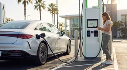 White electric car rental plugged into a charging station along a scenic highway in California