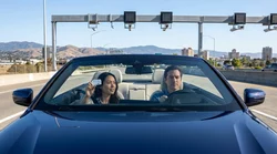 Silver car rental driving across the Golden Gate Bridge in San Francisco under a clear blue sky
