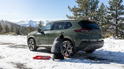 SUV car rental equipped with snow chains driving on a snowy mountain pass in California