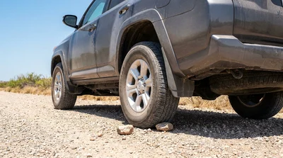 Driver inspecting the windshield and tyres of a white car rental on a rural road in Texas