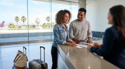 Traveler holding a passport and flight ticket at a car hire counter in Los Angeles
