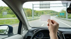White E-ZPass transponder attached to the windshield of a car rental approaching a toll booth in Pennsylvania