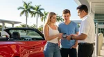 Close up of a young customer handing a credit card to a car rental agent in Miami