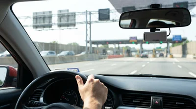 White car hire driving through an electronic toll plaza on a New York highway