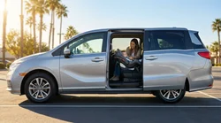 Baby secured in a rear-facing child seat inside a California car rental with sunny palm trees out the window