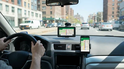 Smartphone displaying a map mounted on the dashboard of a car rental driving through New York