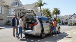 Four adults packing suitcases into the trunk of a car rental on a steep street in San Francisco