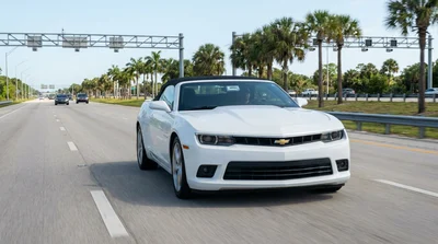 White car rental driving past palm trees and a toll plaza on a sunny Florida highway