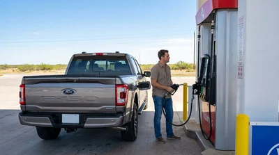 Person pumping fuel into a silver car rental at a gas station in Texas