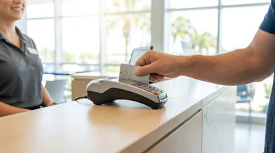 Person inserting a chip credit card into a payment terminal at a Florida car rental desk next to car keys