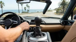 Driver shifting a manual transmission gear stick in a car rental on a highway in the United States