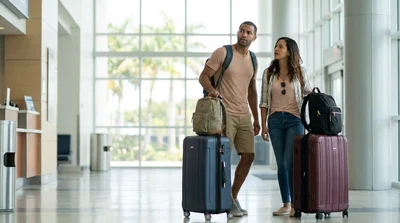 Traveler pulling a suitcase toward a car rental desk at Miami Airport