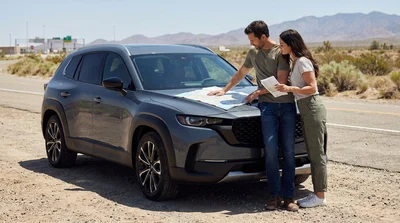 A couple driving a white car rental along a sunny desert highway in California