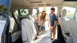 Family buckling seatbelts in the back row of an SUV at an Orlando car rental lot