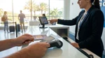 Close up of a person handing a credit card to a car hire agent at a counter in Florida