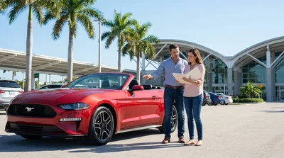 White convertible car rental parked near tall palm trees on a sunny coastal road in Florida
