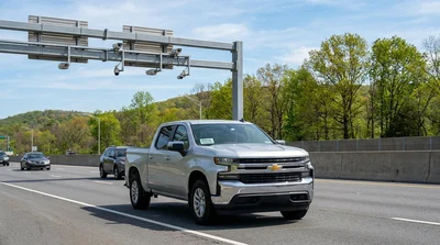 Silver car rental driving through an E-ZPass toll plaza on a Pennsylvania highway
