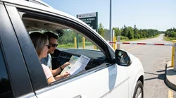 White car rental driving on a scenic highway through a lush green forest in New York