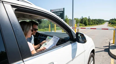 White car rental driving on a scenic highway through a lush green forest in New York
