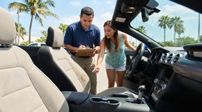 Person inspecting the interior seats and dashboard of a car rental parked outside in sunny Miami