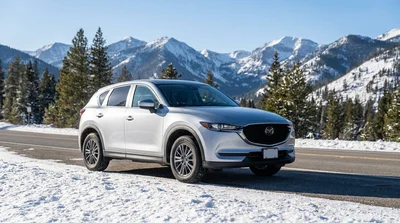 White car rental equipped with snow chains parked on a snowy mountain road in California
