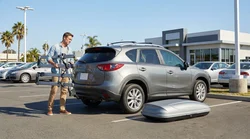 White car rental SUV with a fitted roof box and bike rack parked on a sunny California beach