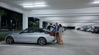 Traveler receiving keys at a brightly lit car hire desk inside Orlando airport at night