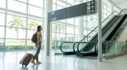 Traveler with luggage walking toward a car rental counter at Miami Airport
