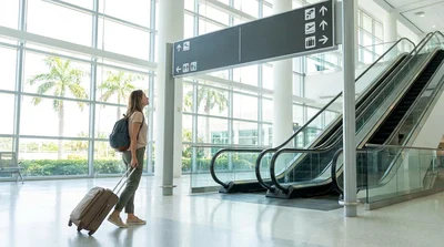Traveler with luggage walking toward a car rental counter at Miami Airport