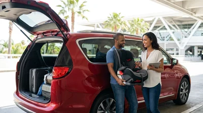 Family loading luggage into a white SUV at a car rental lot in Orlando