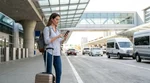 Traveler with luggage waiting at a car hire shuttle pick-up zone outside JFK Airport in New York