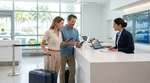 Traveler showing a smartphone to an agent at a car rental desk in Miami