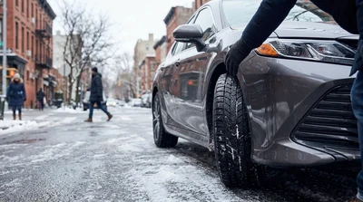 Black car rental with winter tires driving on a snowy New York road