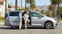 A silver easy-entry SUV car rental with a wide open door parked on a sunny palm-lined Los Angeles street