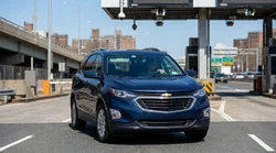 Silver car rental driving through an E-ZPass toll plaza on a New York highway
