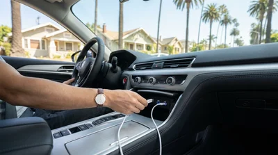 Smartphone plugged into a USB-C charging port on the dashboard of a car rental in Los Angeles
