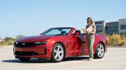 A white car rental driving along a scenic desert highway under a clear sky in Texas