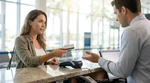 Customer handing a credit card to an agent at a car rental desk in Miami