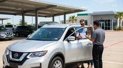 Person showing a temporary paper driving license at a car rental counter in Texas