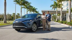 Silver car rental driving on a sunny highway surrounded by palm trees in Florida